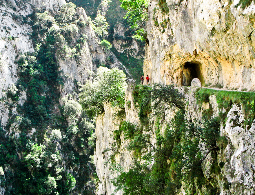 Two persons walking on a thin track in a stone wall