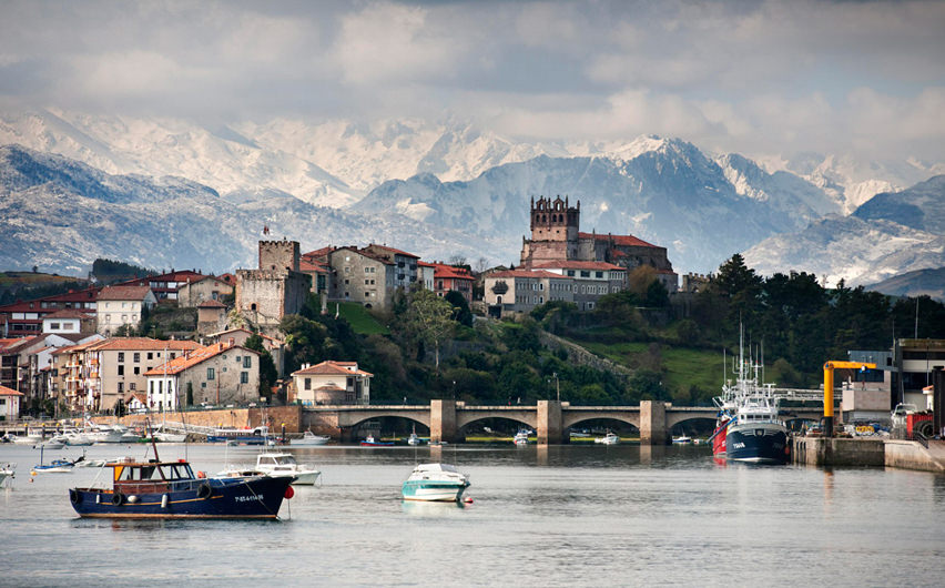 Building of fishermen village with its castle and mountains covered with snow at the back